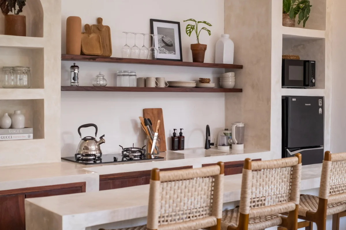 Open keuken met houten planken, kookplaat en rotan barkrukken in een opgeleverde villa